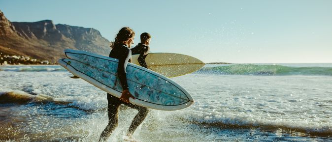 Surfer laufen auf das Meer zu