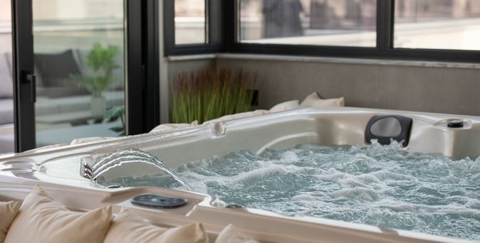 Whirlpool der blubbert und in den Wasser eingelassen wird. Vor dem Whirlpool ist eine Reihe von Kissen