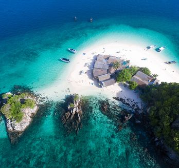 Luftaufnahme einer Insel mit Booten im türkisfarbenen Wasser 