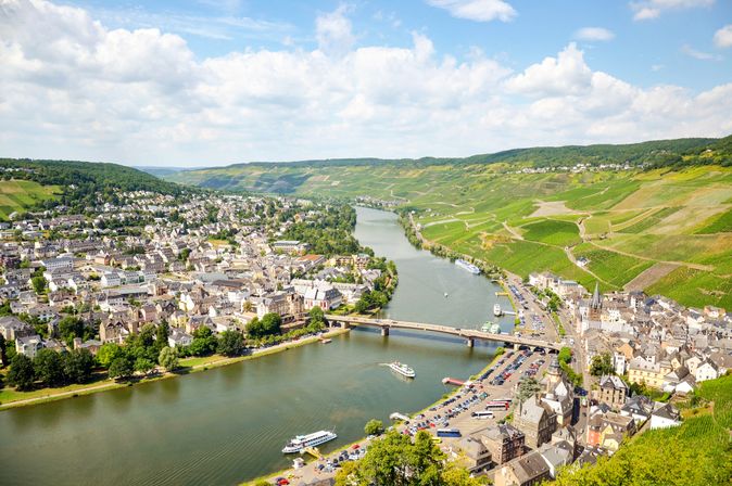 Fluss mit Brücke, die zwei Seiten eines Dorfes inmitten einer grünen Landschaft verbindet