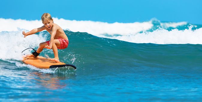 Junge surft auf einer Welle
