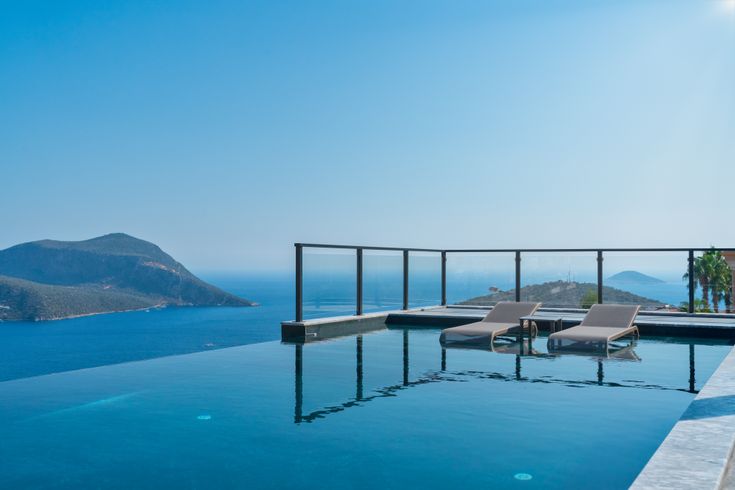 Infinity Pool mit zwei Liegen und dem Meer im Hintergrund