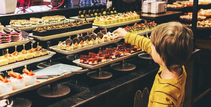 Ein Kind bedient sich an einem Dessertbuffet