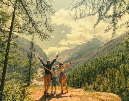 Eltern und Kind schauen beim Wandern gemeinsam auf eine Berglandschaft 