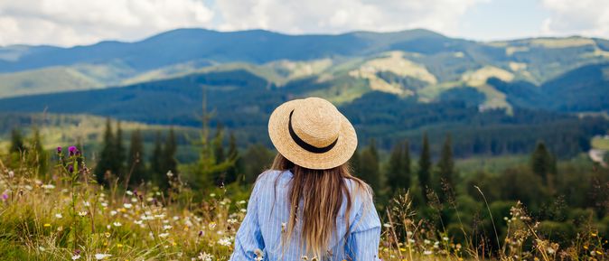 Frau liegt im Gras umgeben von einer Berglandschaft