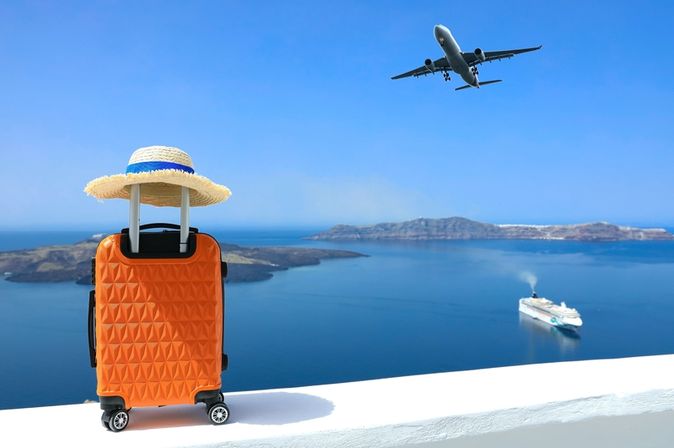 Ein Koffer steht auf einer Mauer, im Hintergrund sieht man das Meer und ein Schiff, im Himmel fliegt ein Flugzeug