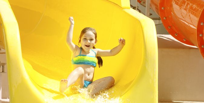 Mädchen rutscht glücklich auf einer Wasserrutsche