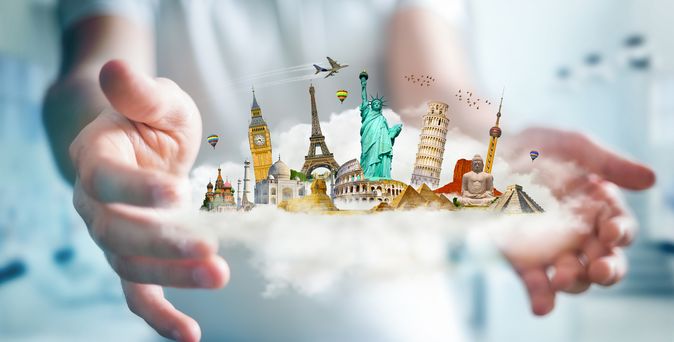 Zwei Hände die eine Wolke hält auf der verschiedene Wahrzeichen, wie der Eiffelturm oder die Freiheitsstatue.