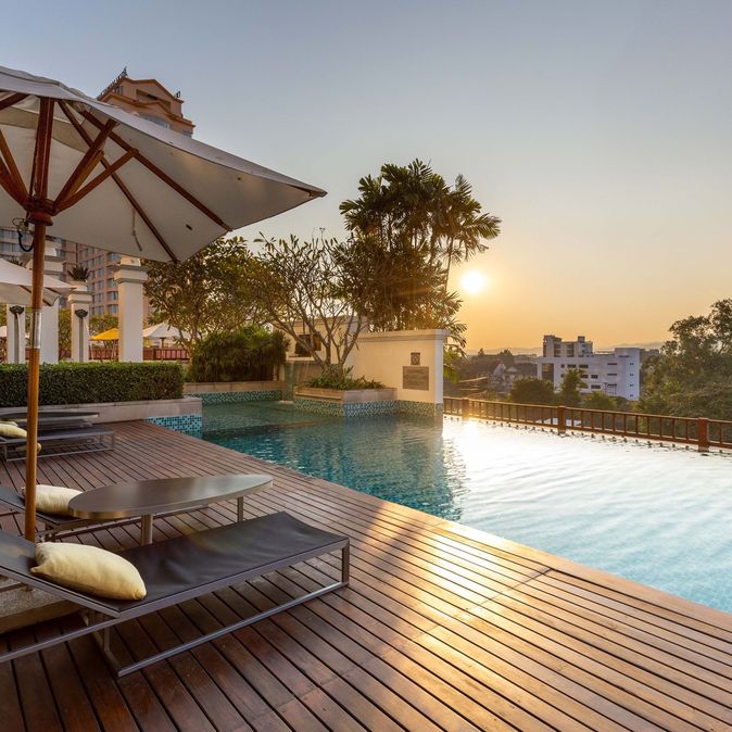 Hotelpool bei Sonnenuntergang mit Liegen und einem Sonnenschirm