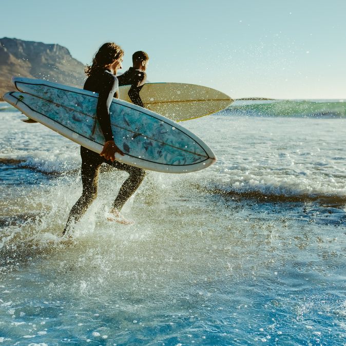 Surfer laufen auf das Meer zu