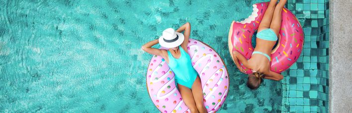 Zwei Frauen liegen in aufblasbaren Ringen in einem Pool