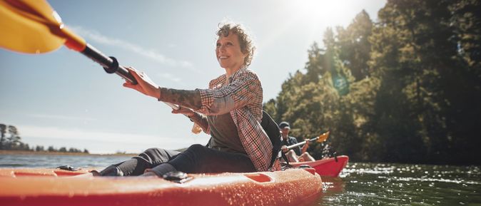 Eine Frau sitzt lächelnd in einem roten Kanu
