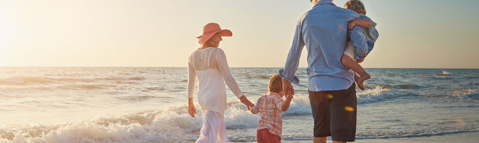 Familie, die einen Strandspaziergang beim Sonnenuntergang macht