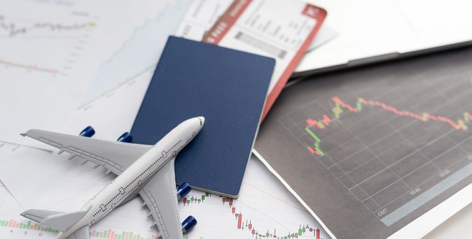 Ein Spielzeugflugzeug liegt mit einem Reisepass und einem Flugticket auf dem Tisch