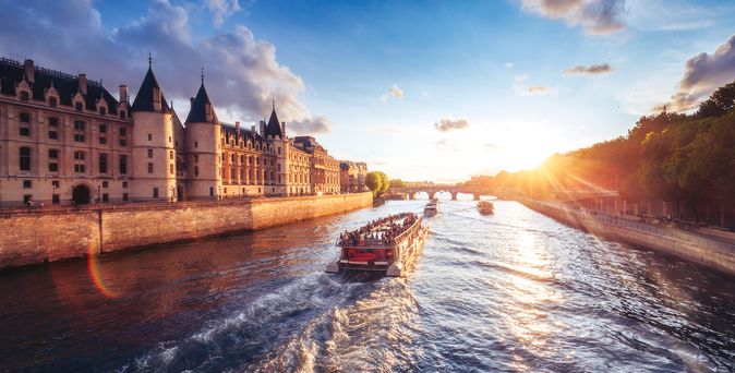 Flusskreuzfahrschiffe fahren an einer Burg entlang bei Sonnenuntergang