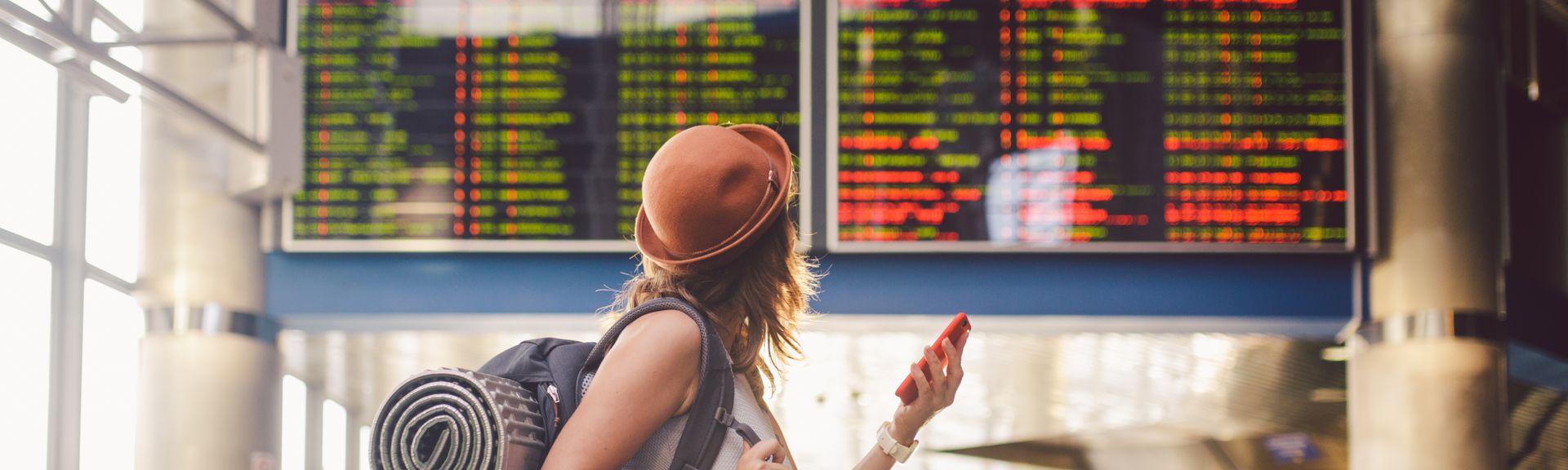 Alleinreisende Frau schaut auf einen Zeitplan am Bahnhof