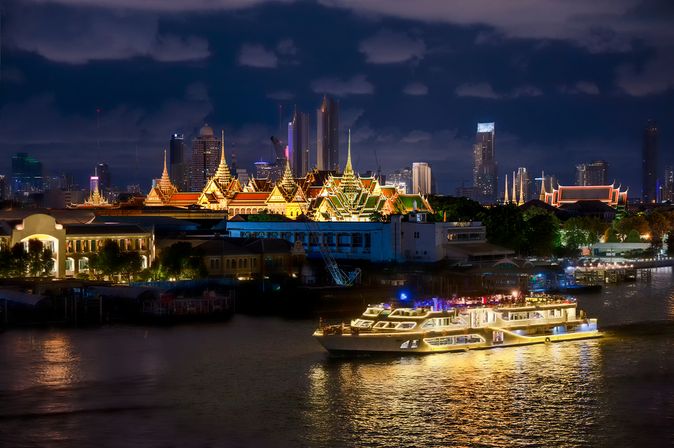 Flusskreuzfahrtschiff bei Nacht, das durch eine Stadt fährt