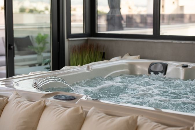Whirlpool der blubbert und in den Wasser eingelassen wird. Vor dem Whirlpool ist eine Reihe von Kissen