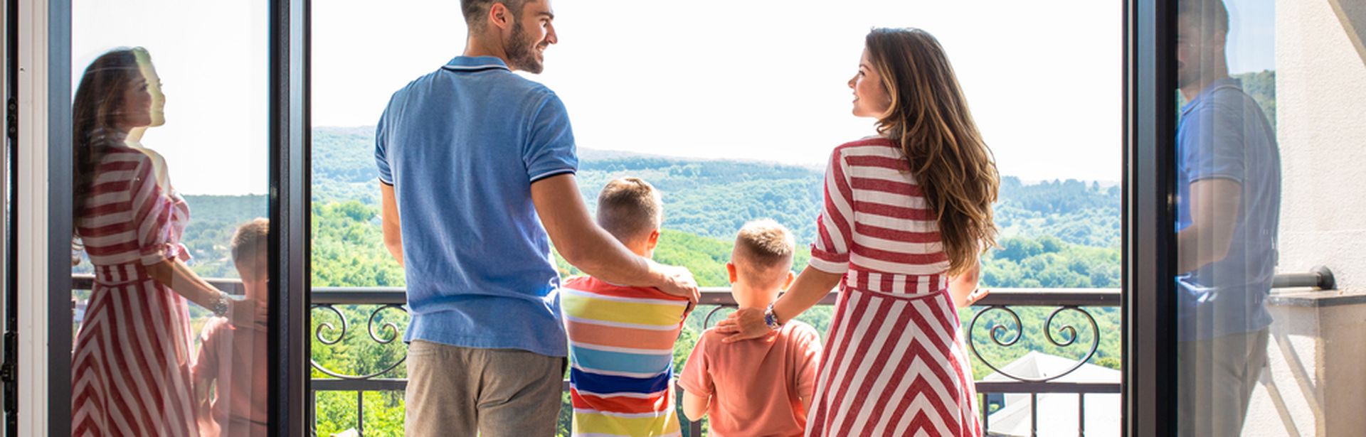 Eine Familie mit zwei Kindern steht Arm in Arm auf einem Balkon 