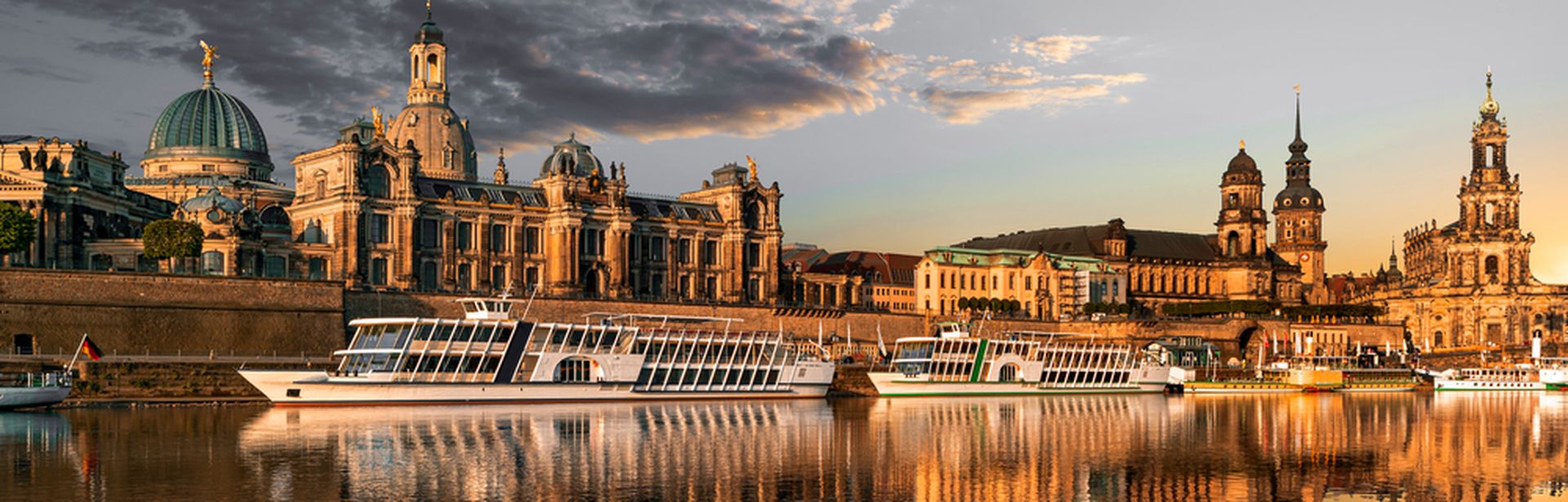 Flusskreuzfahrschiffe fahren an alten Bauwerken vorbei, die sich im stillen Wasser des Flusses spiegeln