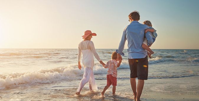 Familie, die einen Strandspaziergang beim Sonnenuntergang macht
