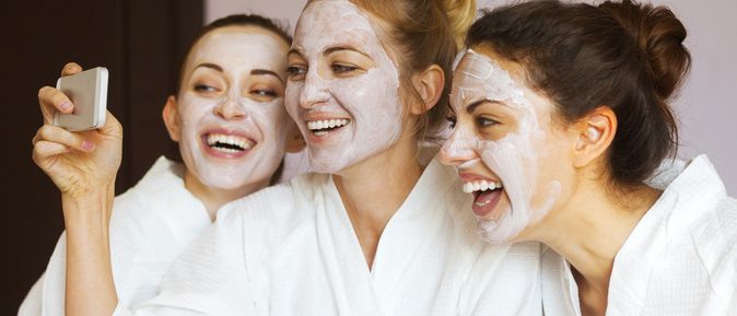 Drei Frauen tragen Gesichtsmasken und machen lachend ein Selfie