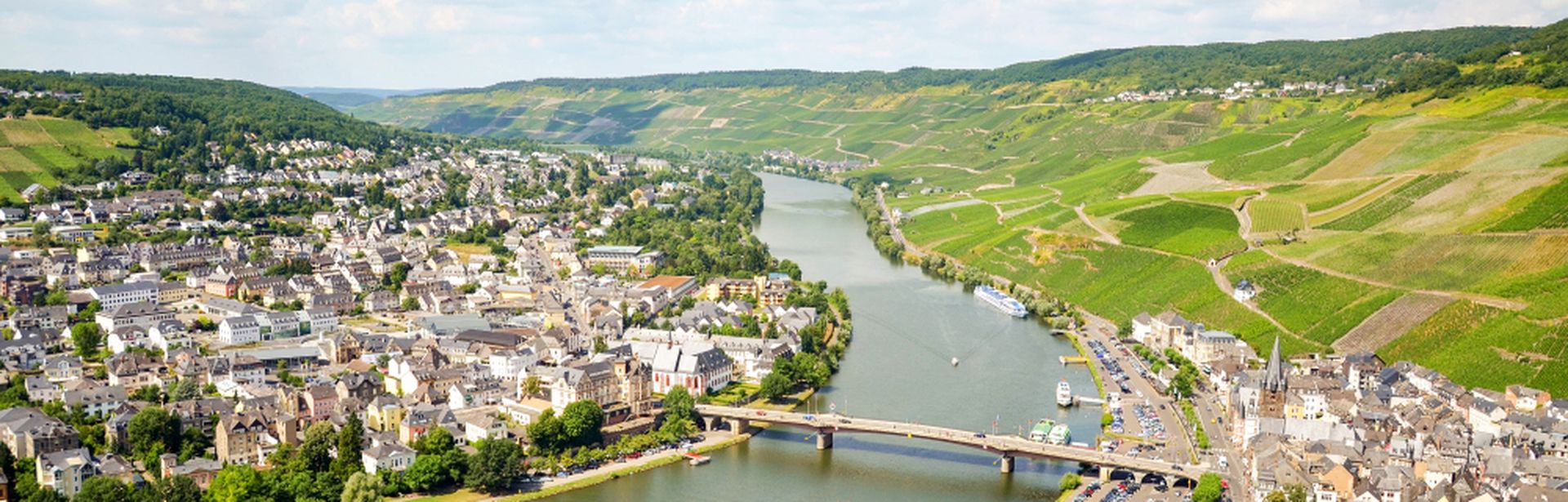 Fluss mit Brücke, die zwei Seiten eines Dorfes inmitten einer grünen Landschaft verbindet