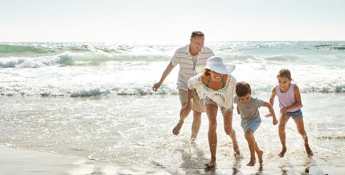 Eine Familie am Strand läuft lachend durch das Wasser