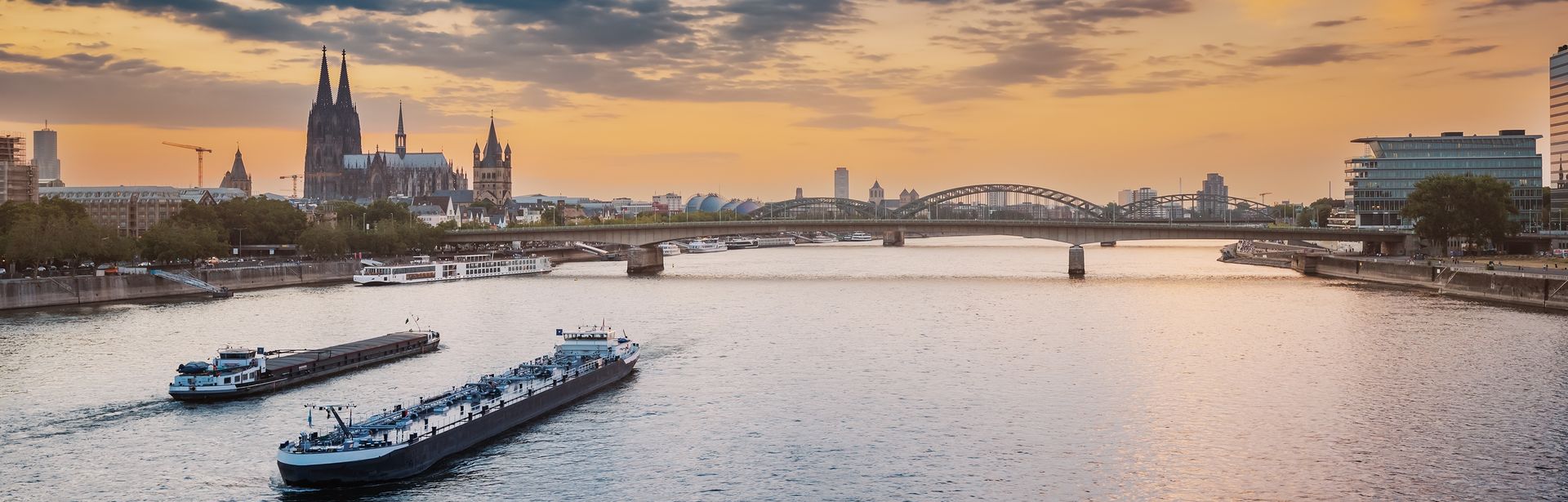 Zwei Flusskreuzfahrschiffe auf einem Fluss, der durch eine Stadt fließt 
