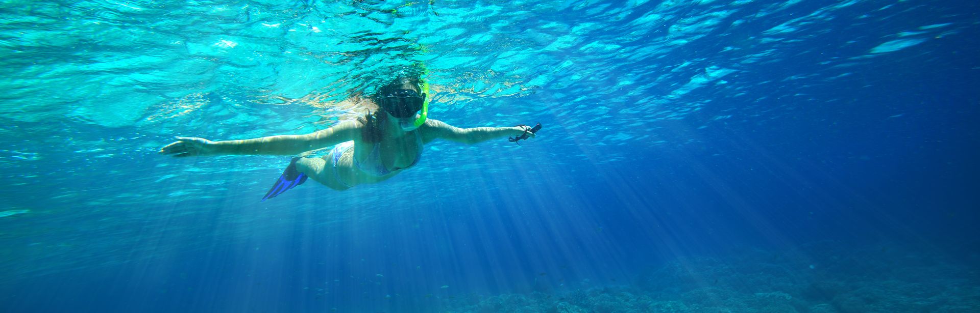 Ein Kind mit Schnorchel im Meer breitet die Arme aus