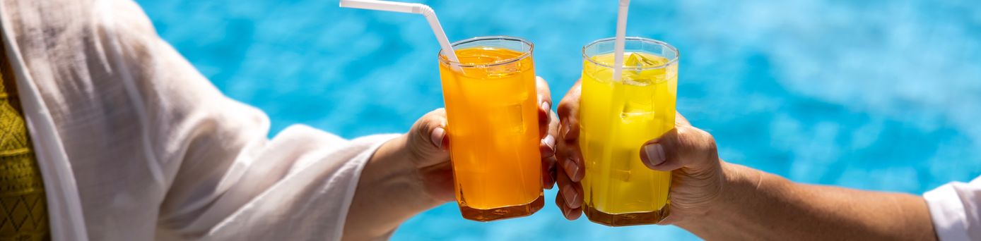 Zwei Hände stoßen mit Gläsern über einem Pool an