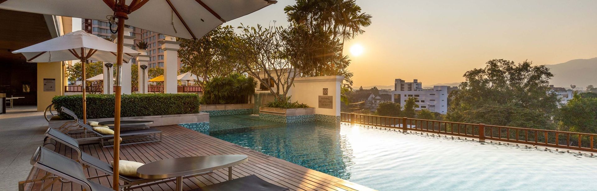 Hotelpool bei Sonnenuntergang mit Liegen und einem Sonnenschirm