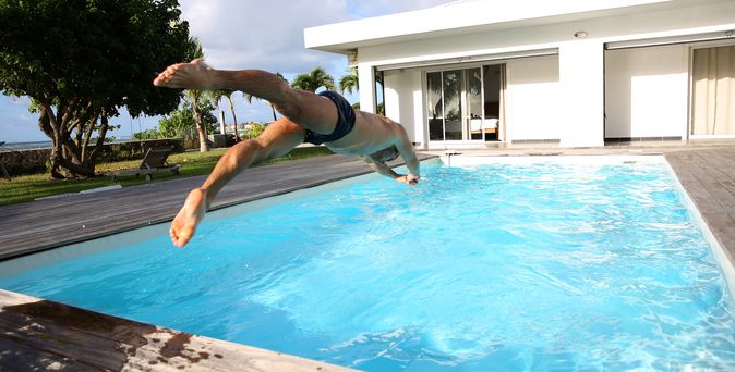 Ein Mann springt Kopfüber in einen großen privaten Pool
