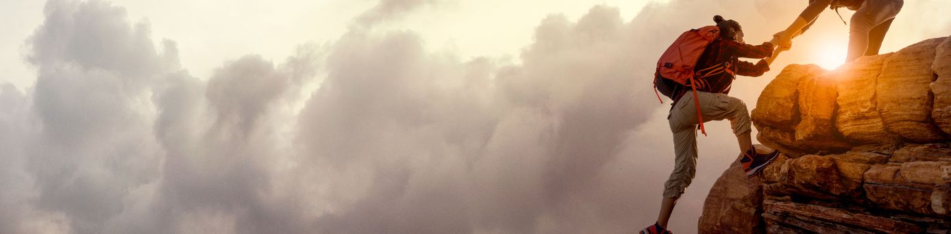 Wanderer bei Sonnenaufgang, Mann hilft Frau einen Berg hoch