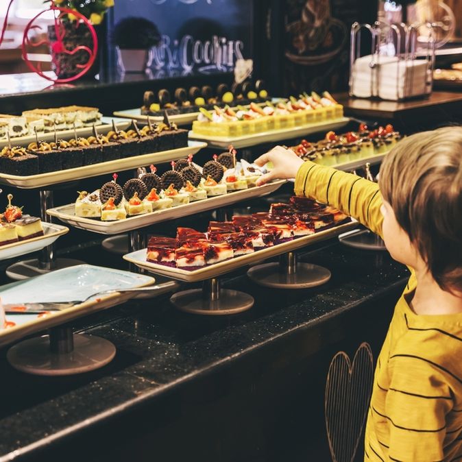 Ein Kind bedient sich an einem Dessertbuffet
