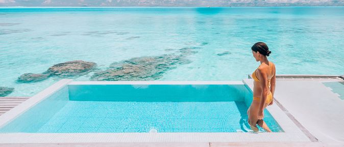 Eine Frau steigt in einen erhöht über dem Strand gelegen Pool