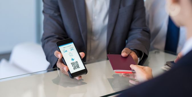 Am Flughafenschalter wird ein Reisepass entgegengenommen und eine Digitale Bordkarte vorgezeigt