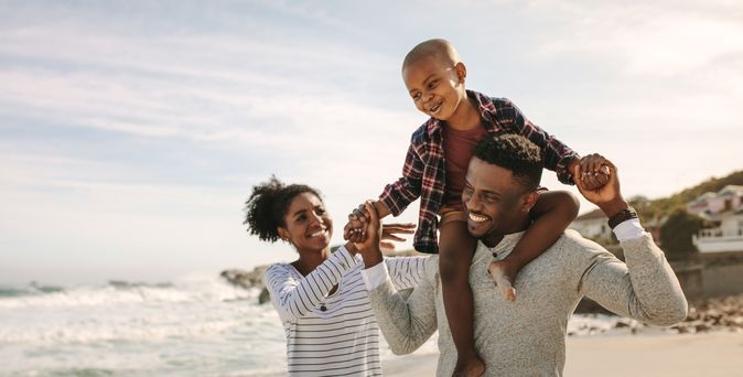 Eine Familie am Strand, Sohn sitzt auf den Schultern des Vaters