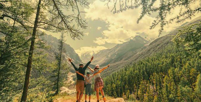 Eltern und Kind schauen beim Wandern gemeinsam auf eine Berglandschaft 