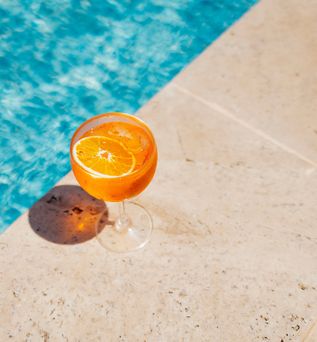 Ein Oranges Getränk steht am Rand eines Pools