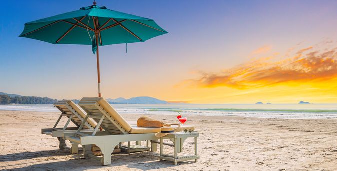 Zwei Liegen mit Sonnenschirm stehen am Strand
