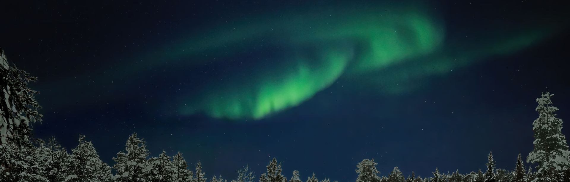 Polarlichter über einer Hütte im schneebedeckten Wald