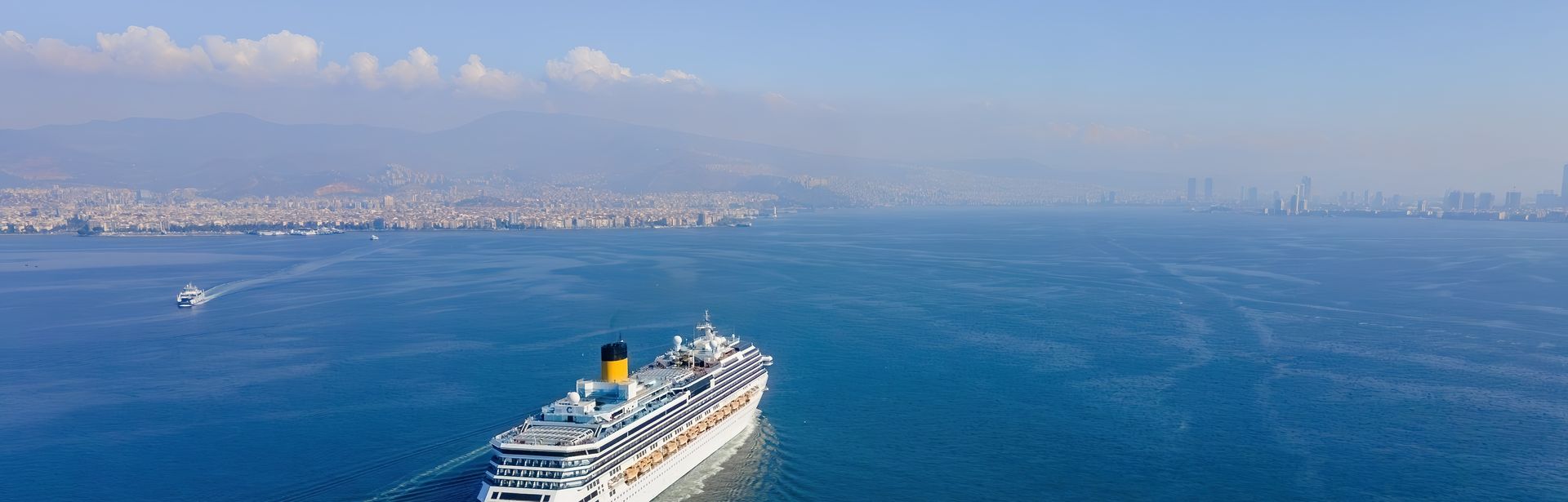 Weißes Kreuzfahrtschiff fährt bei sonnigem Wetter über das Meer
