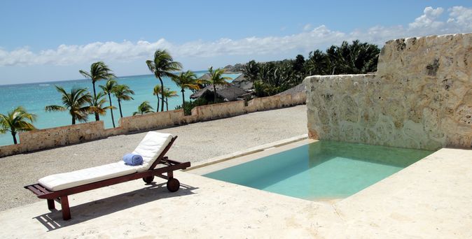 Eine höher gelegene Terrasse mit einem kleinen privaten Pool, einer Liege und Blick auf das Meer und Palmen