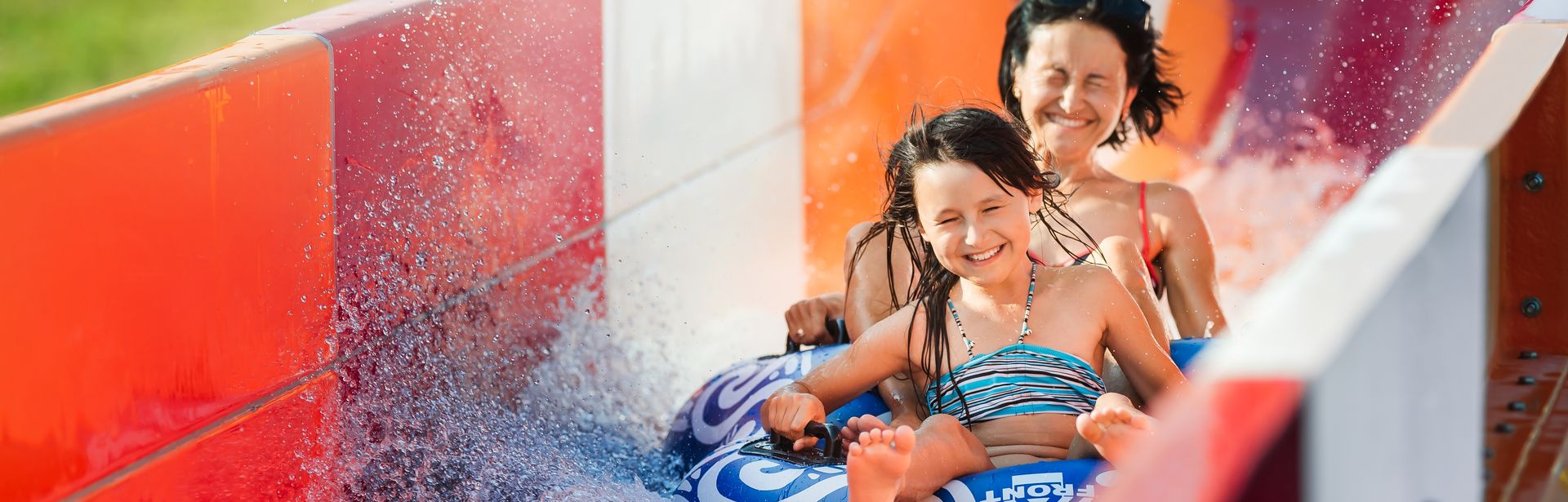 Eine Frau und ein Kind rutschen auf einem Reifen eine rote Wasserrutsche