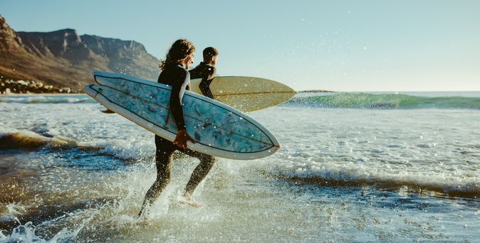 Surfer laufen auf das Meer zu