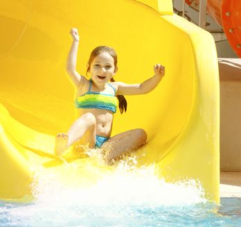 Mädchen rutscht glücklich auf einer Wasserrutsche