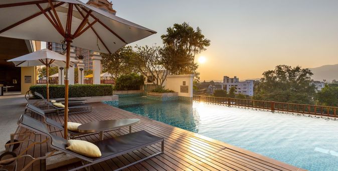 Hotelpool bei Sonnenuntergang mit Liegen und einem Sonnenschirm