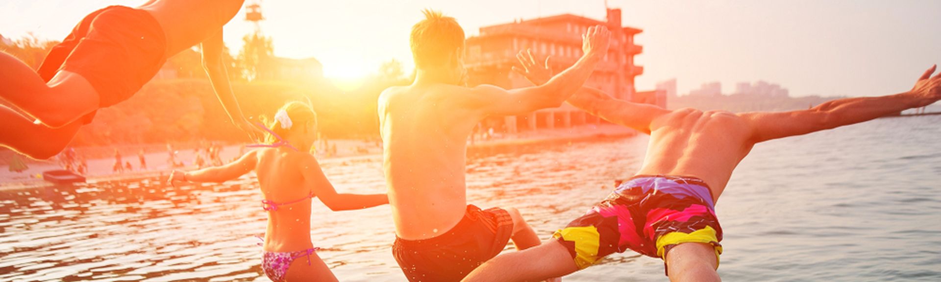 Vier Personen springen bei Sonnenuntergang ins Meer