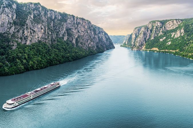 Flusskreuzfahrschiff fährt durch einen Fluss, umgeben von steilen Klippen